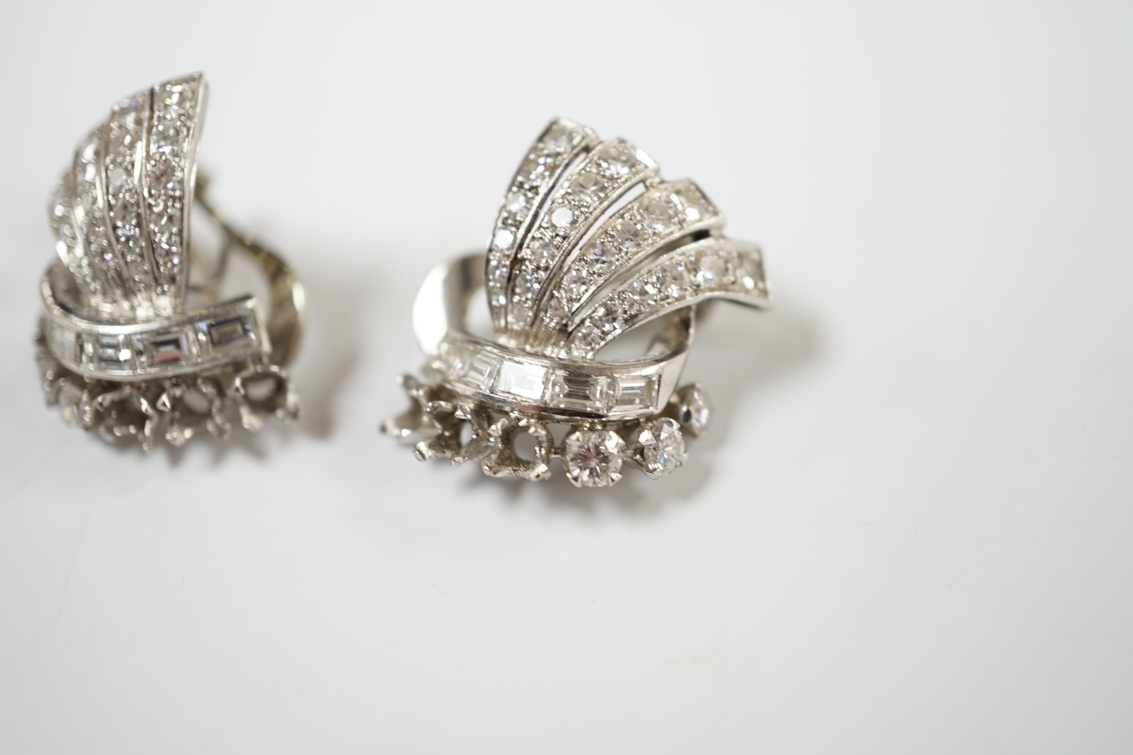 A pair of white metal, round and baguette cut diamond cluster set fan shaped earrings, 20mm, gross weight 10.7 grams (three stones missing from each).